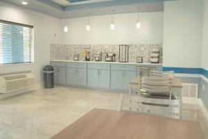 Una cocina con gabinetes azules y una mesa y sillas. en Hotel Royale IAH Airport North Houston I-45, en Houston