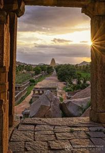 uma vista de uma janela de pedra para um rio com a pirâmide em Vikram Homestay Hampi em Hampi