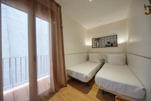 バルセロナにあるアパート スイート オステンプロのベッドが2つと窓がある小さな部屋