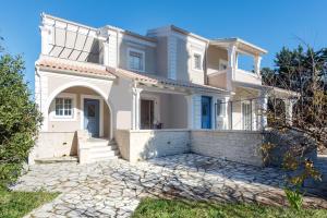 a large white house with a stone driveway at Nancy Luxury Suites in Kassiopi