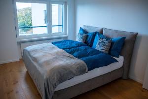 Una cama con sábanas azules y una ventana en una habitación en Seenähe 300 Meter 126 qm Wohnfläche 6 Betten, en Rorschacherberg