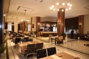 ein Restaurant mit Tischen und Stühlen und eine Bar in der Unterkunft Ziyorat Luxury Hotel in Fargʻona