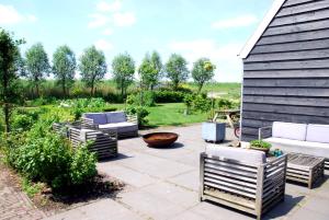 a patio with couches and chairs and a yard at Bed In Waterland in Broek in Waterland