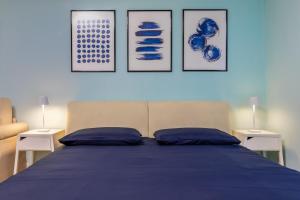 een slaapkamer met een blauw bed met drie schilderijen aan de muur bij Cozy apartment in Castelfranco Veneto