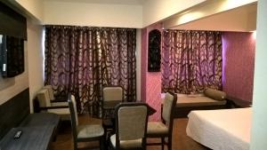 a hotel room with a bed and chairs and curtains at Hotel Supreme in Madurai