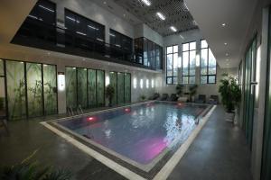 ein großes Schwimmbad in einem Gebäude mit Fenstern in der Unterkunft Ziyorat Luxury Hotel in Fargʻona