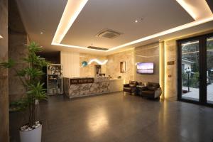 eine Lobby mit einem Wartebereich mit einem Sofa und einer Theke in der Unterkunft Ziyorat Luxury Hotel in Fargʻona