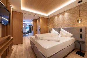 una camera da letto con un grande letto bianco e una televisione di Apart La Vita a Sankt Anton am Arlberg