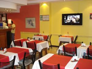 Hotel Esperia في بوينس آيرس: غرفة طعام مع طاولات وتلفزيون على الحائط