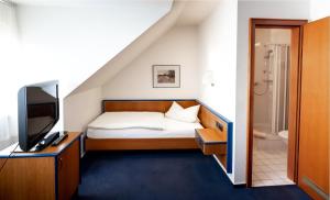 a small bedroom with a bed and a television at Hotel Germania in Stadtallendorf +30 photos