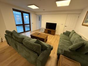 a living room with a green couch and a television at New 4 Bed House Sleeps up to 8 People in Chepstow
