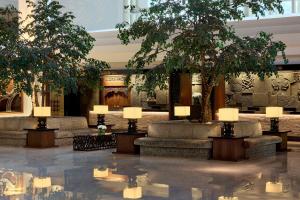 Un vestíbulo con árboles, sillas y luces. en Gran Melia Jakarta, en Yakarta