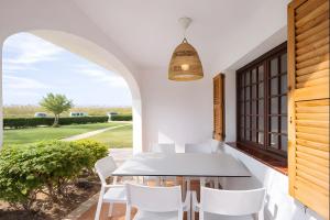 a dining room with a table and white chairs at Son Bou Gardens Plus 1 in Son Bou