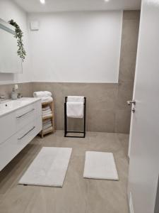 Un baño con lavabo y dos alfombras blancas. en Lakeside Ferienhaus - Parndorf Outlet, en Neusiedl am See 46 fotos más