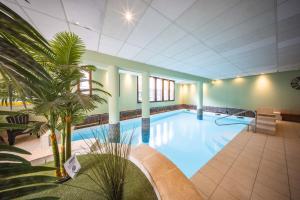 a large swimming pool with palm trees in a building at Le Rioumajou 3 - T3bis - Proche télécabine - St Lary village in Saint-Lary-Soulan