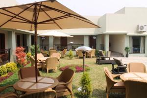 un patio con tavoli, sedie e ombrellone di Hotel Moon Palace Kolwezi a Kolwezi
