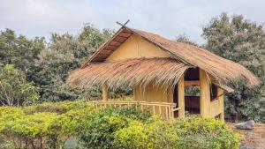 une cabane au toit de chaume dans un champ dans l'établissement Ozone Valley Camp Khaoyai, à Nong Nam Daeng