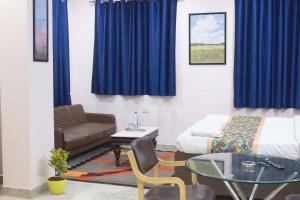 ein Schlafzimmer mit einem Bett, einem Tisch und einer Couch in der Unterkunft JSB Hotel in Faridabad