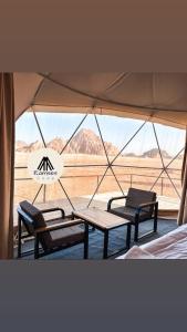 Una tienda de campaña con dos bancos y una mesa y una vista del desierto. en Ramses luxury rum camp, en Wadi Rum