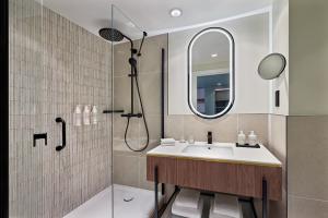 a bathroom with a sink and a shower with a mirror at Le Méridien Paris Arc De Triomphe in Paris
