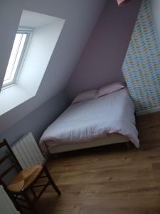 een slaapkamer met een bed en een stoel op zolder bij Lila in Souillé
