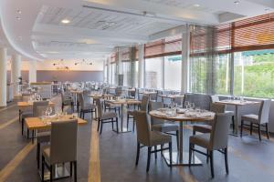 uma sala de jantar com mesas, cadeiras e janelas em Best Western Hotel Sourcéo em Saint-Paul-lès-Dax