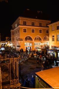 Un grupo de personas caminando alrededor de un edificio por la noche. en 2 - Dolce Antoinette - DonViore, en Győr