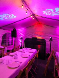 ein langer Tisch in einem Zelt mit violettem Licht in der Unterkunft ENTRE ADOUR et MONTAGNE in Pouillon
