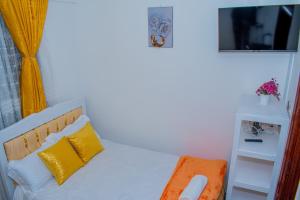 a bedroom with a bed with yellow pillows and a television at Delsy Stays in Ruaka
