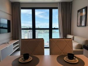 een woonkamer met een tafel en stoelen en een groot raam bij Vista Mar - Suíte, Cozinha Completa, Até 4 pessoas in Itapema +65 foto's
