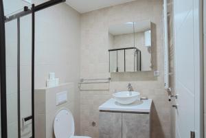 um banheiro com uma pia, um vaso sanitário e um espelho em Hedonist Garden Luxury Apartments em Doboj mais 30 fotografias