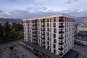 um edifício de apartamentos branco e alto numa cidade em Hedonist Garden Luxury Apartments em Doboj