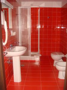 baño de azulejos rojos con 2 aseos y ducha en Santa Loja Hotel Residence, en Tito