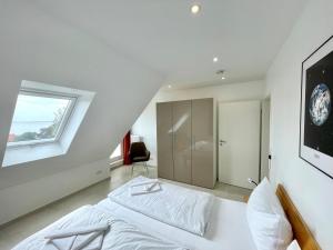 a white bedroom with a bed and a window at Meerblick in Hansaland