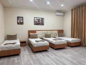 een hotelkamer met drie bedden bij Hotel Moon in Yakkasaray