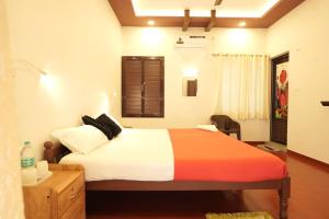 une chambre avec un lit, un bureau et une fenêtre dans l'établissement Marari Lois Beach Homes, à Mararikulam