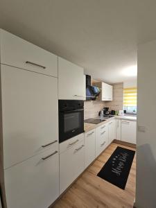 una cocina con armarios blancos y horno negro en Allgaeuerferienwohnung Schneider, en Woringen