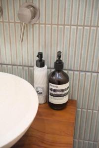 zwei Flaschen mit Duftstoffen auf einer Theke neben einem Waschbecken in der Unterkunft Elegant two-room apartment with garden, 10 min from La Défense in Suresnes