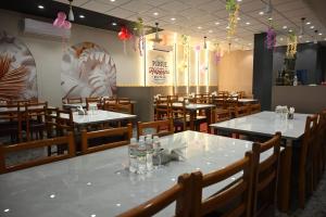 a dining room with white tables and wooden chairs at Hotel Alento in Jamnagar