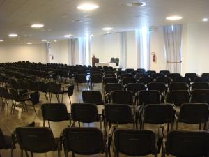 a room filled with chairs and a man standing at a podium at Santa Loja Hotel Residence in Tito