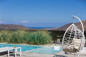 a view of a pool with a chair and a table at Thalmargia Villas, with Pool, Hot Tub & Ultimate Peace, By ThinkVilla in Garazo