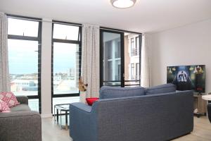 ein Wohnzimmer mit zwei blauen Sofas und großen Fenstern in der Unterkunft Lazarett Loft Modern Apartment in Windhoek