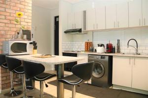 eine Küche mit einem Tisch mit Stühlen und einer Mikrowelle in der Unterkunft Lazarett Loft Modern Apartment in Windhoek