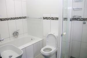 ein weißes Badezimmer mit Toilette und Waschbecken in der Unterkunft Lazarett Loft Modern Apartment in Windhoek + 1 Foto