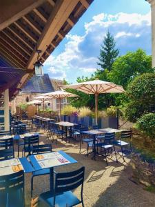 um pátio com mesas, cadeiras e um guarda-sol em Best Western Blanche de Castille Dourdan em Dourdan