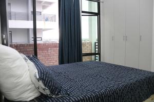 ein Schlafzimmer mit einem Bett und einem großen Fenster in der Unterkunft Lazarett Loft Modern Apartment in Windhoek