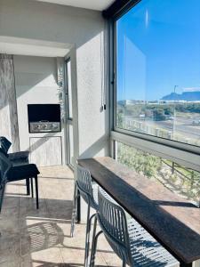 a balcony with a table and chairs and a large window at Stanley's Place at 212 Salerno in Cape Town