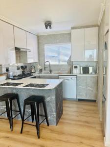 a kitchen with white cabinets and a counter with stools at Stanley's Place at 212 Salerno in Cape Town