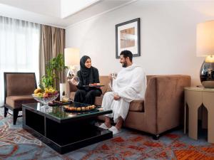 um homem e uma mulher sentados num sofá numa sala de estar em Swissotel Makkah em Meca