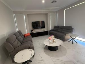 a living room with two couches and a table at Wellard Nest- Perth- Newly built house, walk to the shops and train station- Close to Rockingham and motorplex in Wellard